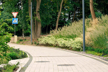 track pavement in park landscaped city natural square place with road sign and lantern pillar in...