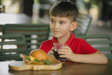 Young boy enjoying burger and drink at cafe