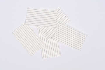 A photo of five rectangular pieces of white plastic twist ties with wire cores, scattered on a light gray surface