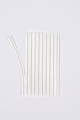 A photo of a bundle of white plastic twist ties with wire cores, with one of the ties partially separated from the main group