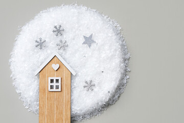 Top view of a wooden house on artificial snow on a gray background.