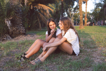 Portrait of two teen girls sitting on the grass. Best friends enjoying themselves in the park