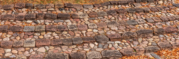 Panoramic image. Old outdoor staircase in a park covered by autumn leaves