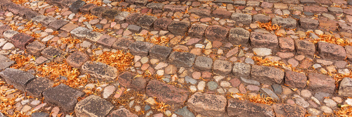 Panoramic image. Old outdoor staircase in a park covered by autumn leaves
