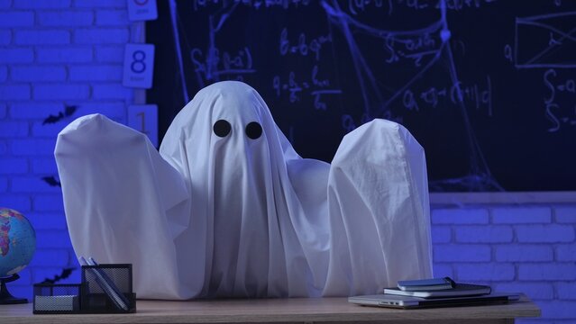 A person in a white ghost sheet scares students