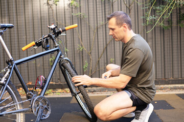 Obraz premium Caucasian male cyclist checking his road bike tire. Part of bicycle. Close-up of male hands fixing bike Wheel. Bike maintenance.