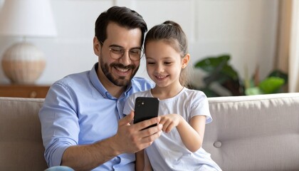 A young girl and her father looking at a mobile phone. Two generations learning technology together