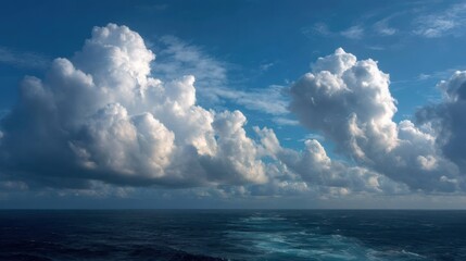 Vast ocean under a bright blue sky filled with large, fluffy cumulus clouds.