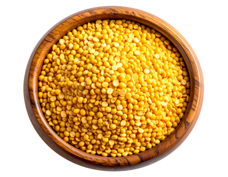 A dark-wood bowl overflows with vibrant, golden-yellow split peas, filling the frame from an overhead perspective.  The peas are small, round, and appear dry