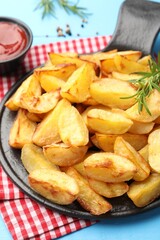 Tasty baked potatoes with rosemary on light blue wooden table, closeup