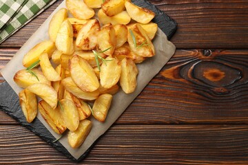 Tasty baked potatoes with rosemary on wooden table, top view. Space for text