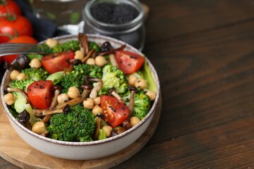 Delicious salad with shimeji mushrooms, chickpeas, tomatoes and broccoli on wooden table, closeup. Space for text