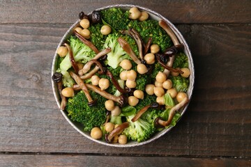 Delicious salad with shimeji mushrooms, chickpeas and broccoli in bowl on wooden table, top view