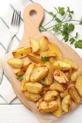Tasty baked potatoes with parsley on white wooden table, flat lay