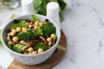 Delicious salad with shimeji mushrooms, chickpeas and broccoli in bowl on white marble table, closeup. Space for text