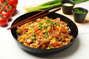 Tasty fried rice and chopsticks on white marble table, closeup