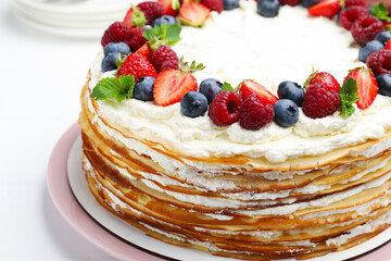 Delicious crepe cake with fresh berries on white table, closeup