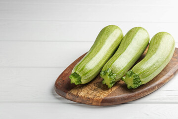 Fresh ripe zucchinis on white wooden table, closeup. Space for text
