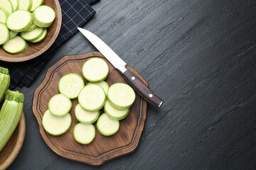 Fresh ripe zucchinis with knife on black textured table, flat lay. Space for text