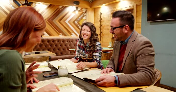 Group of friends reading menu deciding what to order for dinner at a restaurant