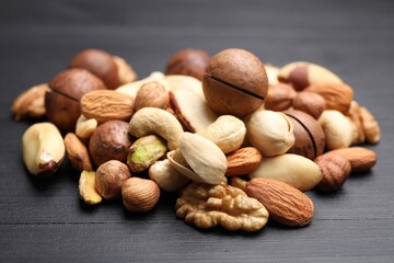 Mix of different nuts on black wooden table, closeup
