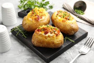 Tasty stuffed baked potatoes served on grey textured table, closeup