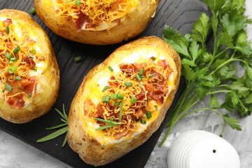 Tasty stuffed baked potatoes on grey table, flat lay