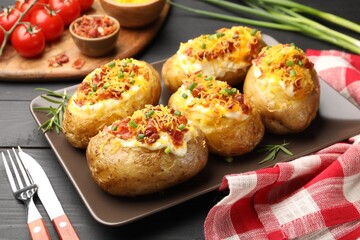 Tasty stuffed baked potatoes served on black wooden table, closeup