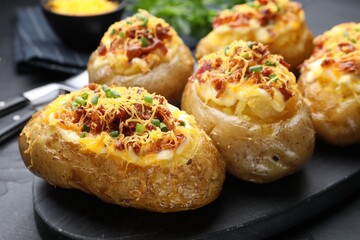 Tasty stuffed baked potatoes on black table, closeup