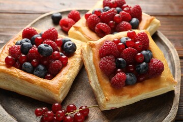 Tasty puff pastries with berries on wooden table, closeup