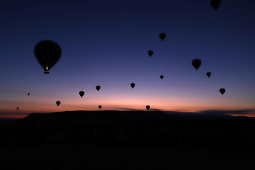 Flying hot air balloons rise in sunrise Cappadocia.