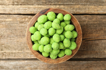 Delicious wasabi coated peanuts in bowl on wooden table, top view