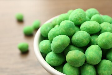 Delicious wasabi coated peanuts in bowl on table, closeup. Space for text