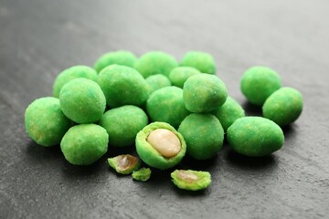 Pile of delicious wasabi coated peanuts on dark textured table, closeup
