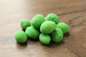 Pile of delicious wasabi coated peanuts on wooden table, closeup