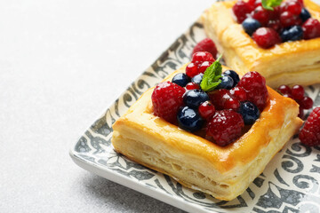 Tasty puff pastries with berries and mint on light grey table, closeup. Space for text