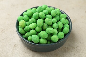 Delicious wasabi coated peanuts in bowl on grey textured table, closeup