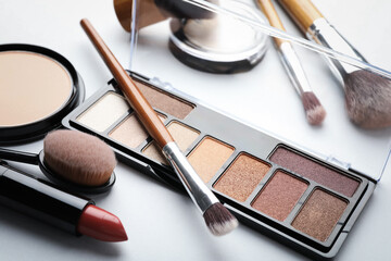 Eyeshadow palette, other cosmetic products and brushes on white background, closeup