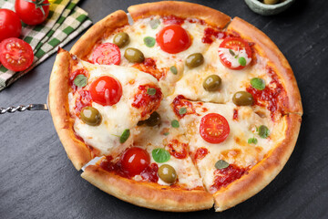 Taking piece of delicious pizza with cheese, tomatoes and olives at dark grey table, closeup