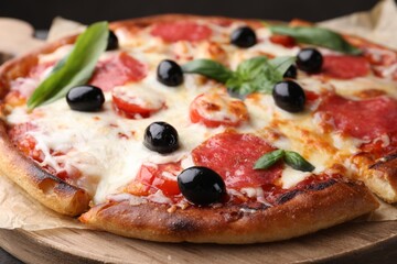 Delicious pizza with cheese, salami, olives and basil on wooden board, closeup