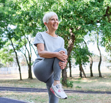 Portrait of a senior mature woman exercising, stretching, warming up, running and jogging outdoors in the park