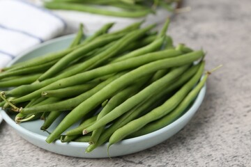 Fresh green bean pods on grey textured table, closeup
