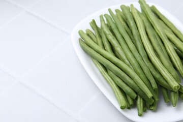 Fresh green bean pods on white tiled table, closeup. Space for text