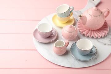 Beautiful ceramic tea set for children on pink wooden table. Space for text