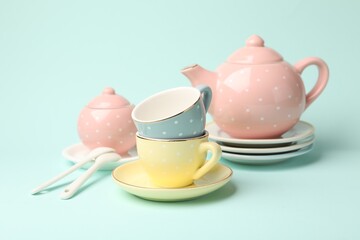 Beautiful ceramic tea set for children on turquoise background, closeup