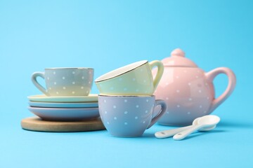Beautiful ceramic tea set for children on light blue background, closeup