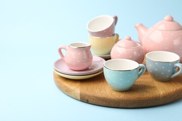Beautiful ceramic tea set for children on light blue background, closeup. Space for text