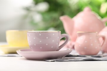 Beautiful ceramic tea set for children on white wooden table against blurred background, closeup