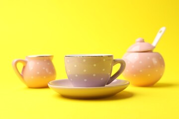 Beautiful ceramic tea set for children on yellow background, closeup