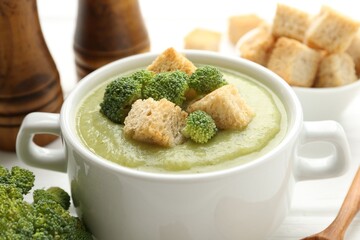 Tasty broccoli cream soup with croutons on table, closeup